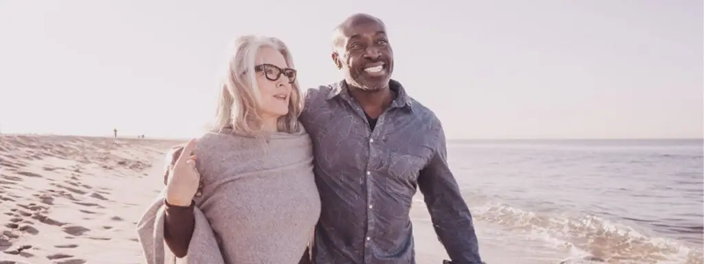 Older couple embraced walking on the beach.